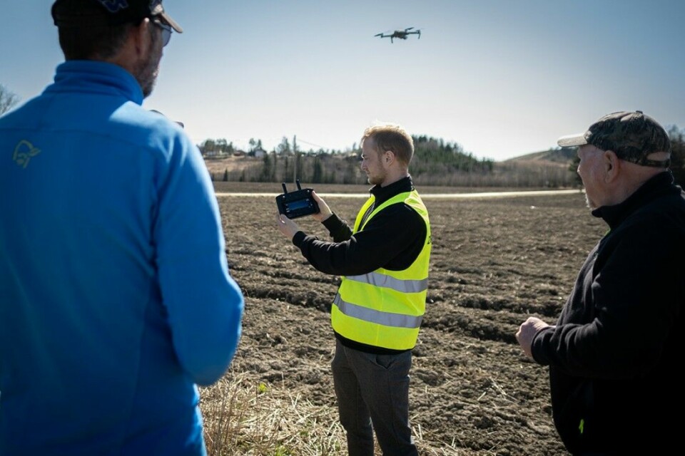 Per Øyvind Alvim (til venstre) og Tore Paulsen (til høyre) fra Eidsberg JFF følger nøye med når Mathias Weber (i midten) fra droneprodusent DJI instruerer i droneflyving på et jorde i Indre Østfold kommune.