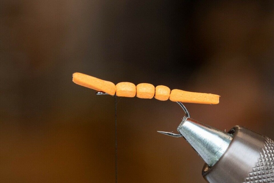 Løft opp foamen som peker framover og surr deg framover med bindetråden til du er ca. en millimeter foran krokspissen. Brett foamen framover og fest den med ett løst turn som du gradvis strammer. Legg ytterligere ett turn med bindetråd på samme plass før du igjen løfter opp foamen og surrer deg videre framover. Gjenta prosessen slik at du får ytterligere et segment. Det tredje og siste segmentet fester du på samme måte, men denne gang med fire trådsurringer. Hold avstand til krokøyet – som vist på bilde 4. Løft opp foamen som peker framover og surr deg framover med bindetråden til du er ca. en millimeter foran krokspissen. Brett foamen framover og fest den med ett løst turn som du gradvis strammer. Legg ytterligere ett turn med bindetråd på samme plass før du igjen løfter opp foamen og surrer deg videre framover. Gjenta prosessen slik at du får ytterligere et segment. Det tredje og siste segmentet fester du på samme måte, men denne gang med fire trådsurringer. Hold avstand til krokøyet – som vist på bilde 4.