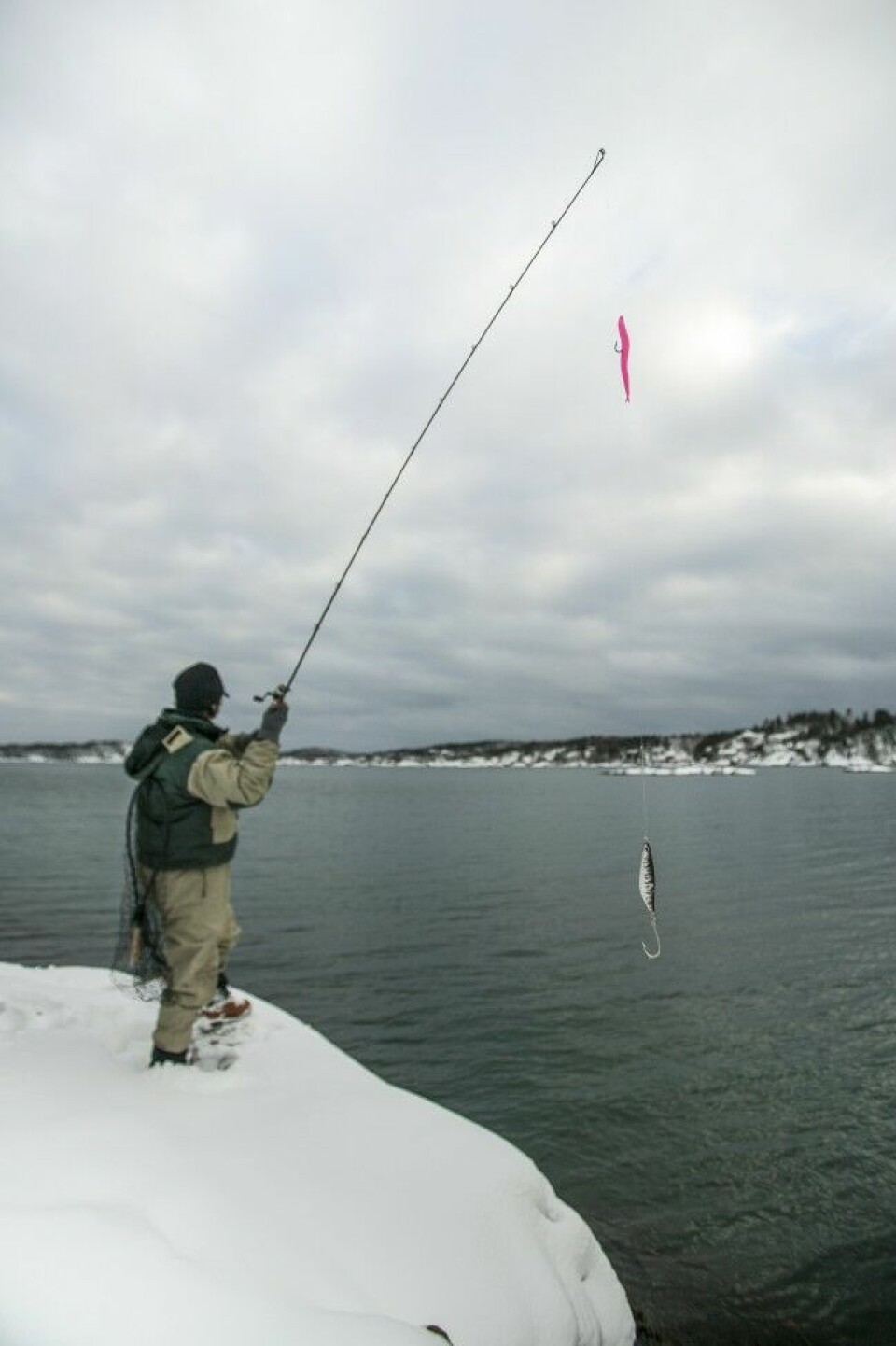 Fiske etter pelagisk fisk som sei, lyr, torsk og sjøørret på snødekket svaberg i Sør-Norge. Foran fiskeren stuper fjellsiden 10 meter rett ned og er et ypperlig utgangspunkt for et problemfritt og effektivt fiske.
