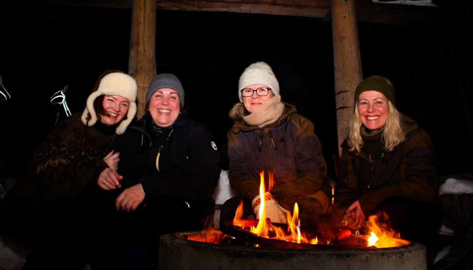 Kvinner ved bål i gapahuk om vinteren