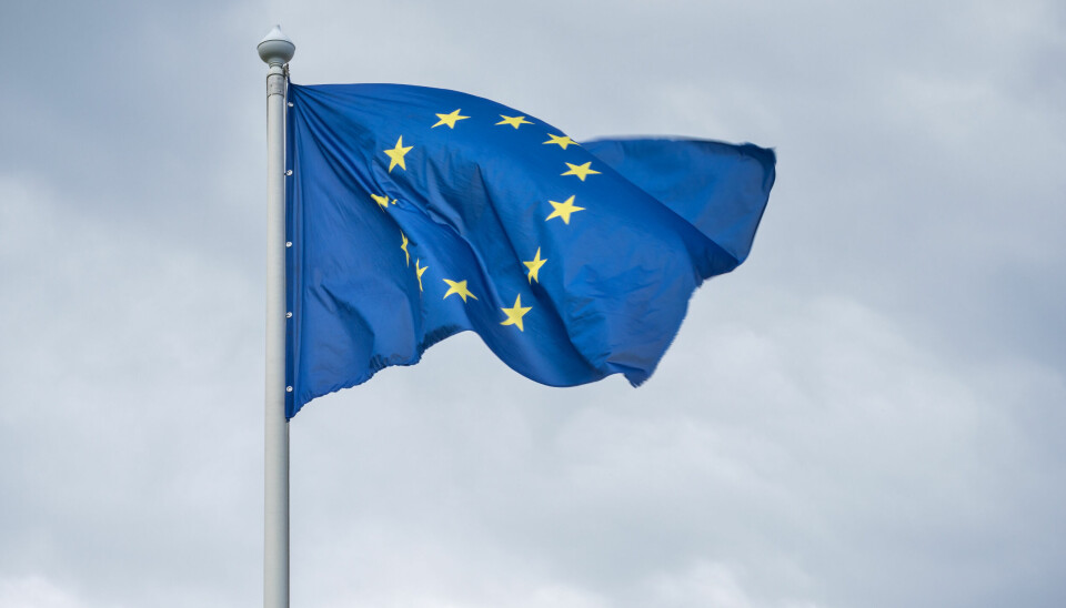 EU sitt flagg vaiende i vinden med gråe skyer i bakgrunnen.