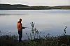 Bildet viser en fisker ved et stille vann i Finnmark. Lyst til å fiske i Finnmark uten å bli spist opp av mygg? Her får du gode råd til når og hvor du skal dra.