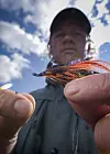 Bildet viser en fluefisker som knyter en Ally’s Shrimp på fortommen til fluestanga.